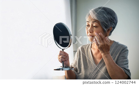 拿著手鏡的老年婦女。我擔心皺紋和瑕疵。 拿著手鏡的老年婦女。我擔心皺紋和瑕疵。 124002744
