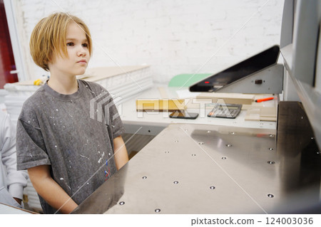 teen girl looking at the professional paper cutter in a printing house teen girl looking at the professional paper cutter in a printing house 124003036