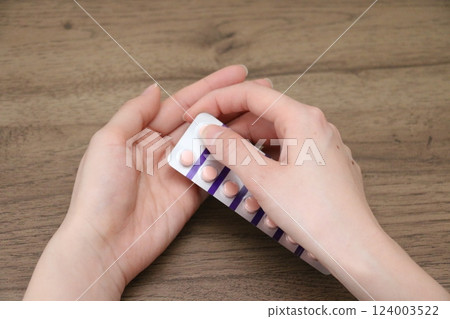 一名婦女的手正準備服用口服藥物 一名婦女的手正準備服用口服藥物 124003522