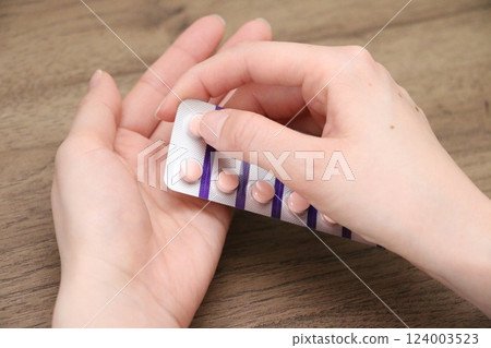 The hand of a woman in her 30s holding a pill of medication The hand of a woman in her 30s holding a pill of medication 124003523
