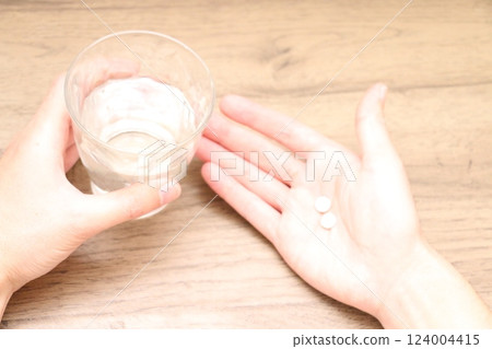 A man's hand about to take a pill and a glass of water A man's hand about to take a pill and a glass of water 124004415