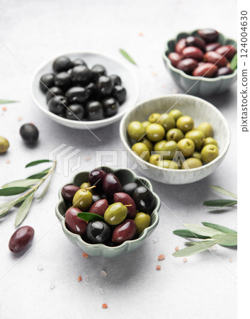 Assorted olives in decorative bowls on white surface Assorted olives in decorative bowls on white surface 124004630
