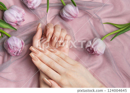 Woman showing nude manicure on pink background with tulips 124004645
