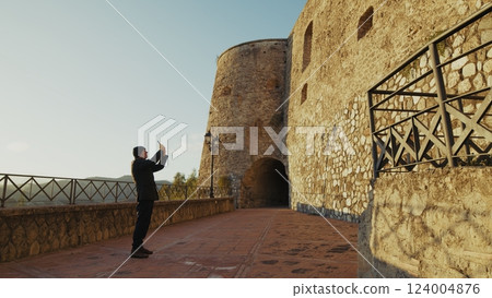 Elderly Man Tourist Observes a Historic Building Defensive Castle in Calabria 124004876