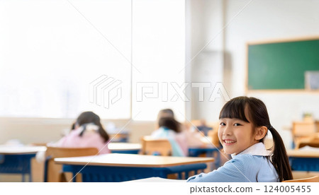A girl sitting in a classroom, looking back at the camera with a smile A girl sitting in a classroom, looking back at the camera with a smile 124005455