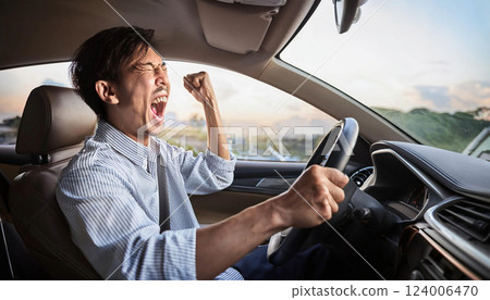 A man yelling and pumping his fist while driving 124006470