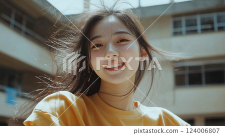 Cheerful chinese student grinning, hair flowing freely near campus architecture 124006807