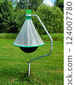 Horsefly trap against green trees. Photo of black ball insect trap on stand in mown meadow. Agricultural equipment for insect protection. 124007780