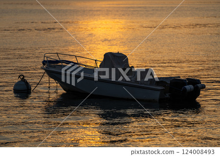 Boat at Sunset with Golden Reflections on Calm Water at Varenna, lake Como, Italy 124008493