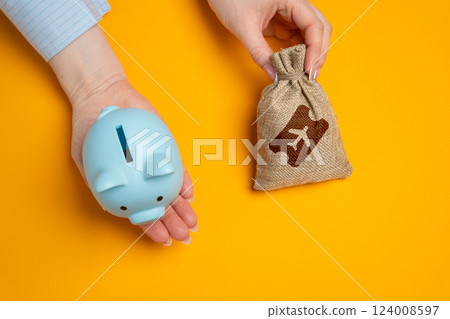 Piggy bank and a bag of airline tickets. The concept of saving on flights, accumulating bonuses and air miles. Discounts and promotions, great deals. Low-cost airlines. Reducing travel costs. Piggy bank and a bag of airline tickets. The concept of saving on flights, accumulating bonuses and air miles. Discounts and promotions, great deals. Low-cost airlines. Reducing travel costs. 124008597