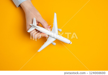 Woman playing with miniature passenger plane. Concept of flights, travel and tourism. Excitement of upcoming trips. Tourism trends, vacation ideas 124008600