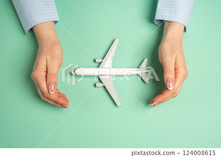 Hands in a gesture of protection of a passenger plane. Protection of the air transport industry. Travel insurance, air travel. Passenger safety. Aviation security. 124008615