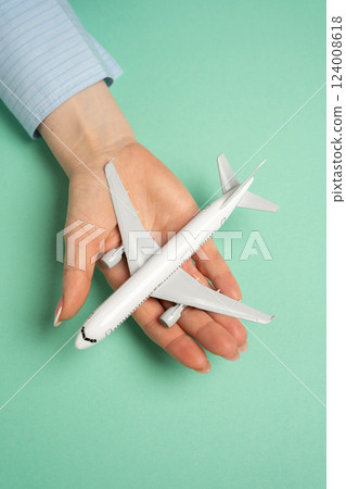 An airline passenger plane in the palm of a woman's hand. Flight ticket booking concept. Flight reservations, travel planning, vacation preparations. Airline ticket sales, booking services, tourism 124008618