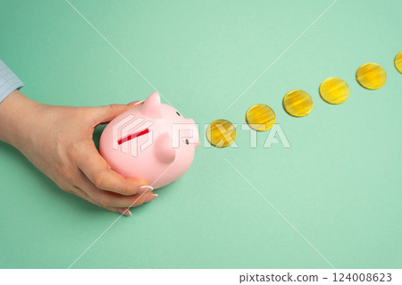 A hand leads a piggy bank along a trail of gold coins. Concept of accumulation of savings. Steady savings growth, financial planning, and building wealth. Budgeting strategies 124008623