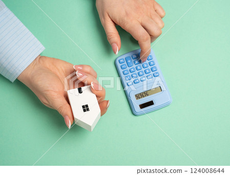 A women uses a calculator to calculate the cost of mortgage payments for a house. Household bills. Financial planning for homeownership, and evaluating household expenses. Mortgage strategies A women uses a calculator to calculate the cost of mortgage payments for a house. Household bills. Financial planning for homeownership, and evaluating household expenses. Mortgage strategies 124008644