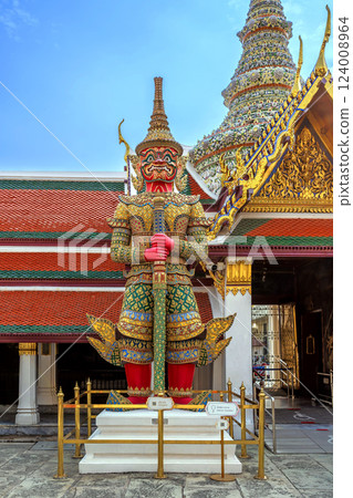 Majestic Yaksha guardian statue with red skin and intricate golden armor stands in front of an ornate Wat Phra Kaew, symbolizing protection and mythology in Thai culture. Majestic Yaksha guardian statue with red skin and intricate golden armor stands in front of an ornate Wat Phra Kaew, symbolizing protection and mythology in Thai culture. 124008964