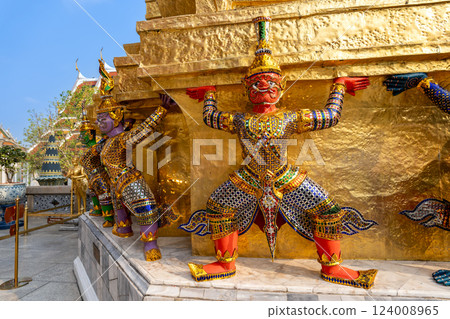 Yaksha guardian statues supporting a golden stupa at Wat Phra Kaew, Bangkok, Thailand. Ornate Thai temple architecture with intricate details and vibrant decorations. Yaksha guardian statues supporting a golden stupa at Wat Phra Kaew, Bangkok, Thailand. Ornate Thai temple architecture with intricate details and vibrant decorations. 124008965