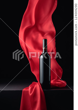 Bottle of red wine and flutters of red cloth. 124009290