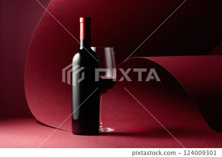 Bottle and glass of red wine on a red background. 124009301