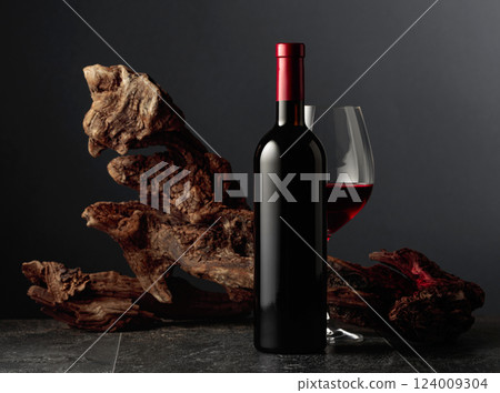 Red wine and old weathered snag on a black stone table. 124009304