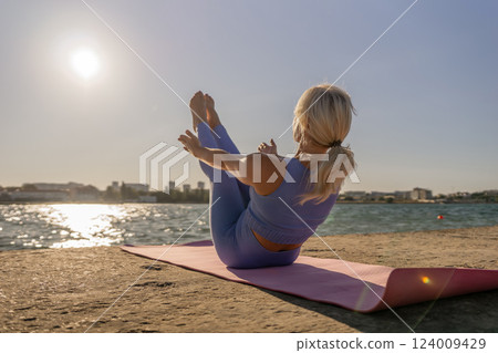 Yoga Beach Woman - Woman practicing yoga on a beach mat at sunset. Yoga Beach Woman - Woman practicing yoga on a beach mat at sunset. 124009429