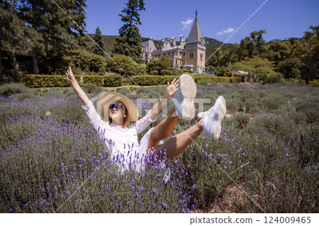 A woman is laying in a field of purple flowers, wearing a white dress 124009465