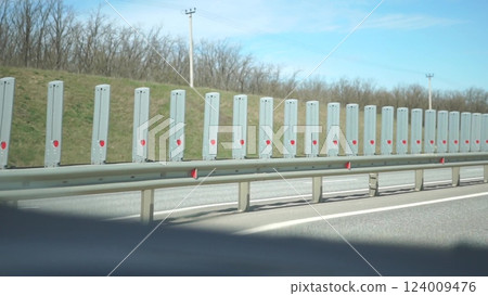 Highway Barriers Safety Roadside Protection - Rows of white barriers line a highway to protect drivers from dangerous roadside conditions. 124009476