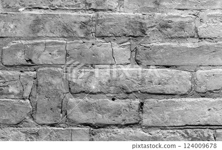 Ancient rough gray brick wall with cracks and holes, close-up 124009678