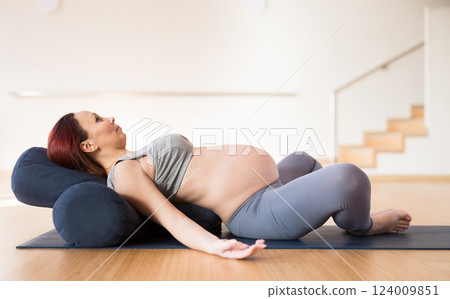 Pregnant woman is engaged in yoga. Reclined Bound Angle Pose or Supta Baddha Konasana 124009851