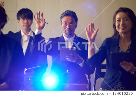 Seminar participants facing forward and raising their hands 124010230