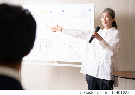 Senior woman giving a speech in front of a whiteboard 124010235