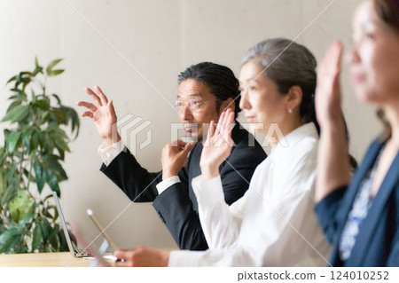 Middle-aged seminar participants raising their hands to ask questions 124010252