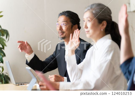 Middle-aged seminar participants raising their hands to ask questions 124010253