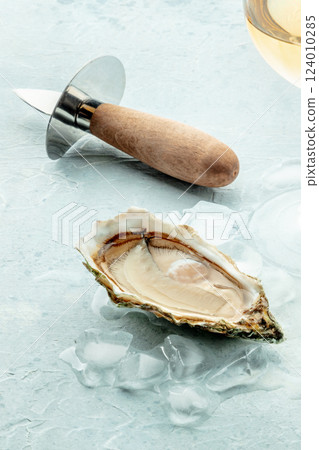 Oyster with a glass of wine, on ice, on a slate background Oyster with a glass of wine, on ice, on a slate background 124010285