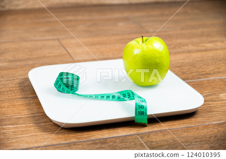Diet Fruit on Scale with Tape Measure Concept. Weight Control and Weight Loss Idea Diet Fruit on Scale with Tape Measure Concept. Weight Control and Weight Loss Idea 124010395