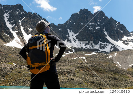 woman hiking with backpack in mountains, landscape during relaxation, rest stop during trekking or hiking 124010410