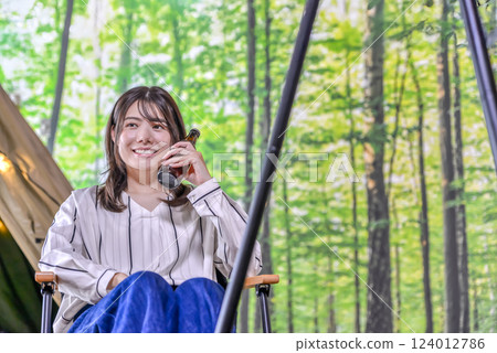 Glamping: Young woman sitting in a hammock and drinking beer 124012786