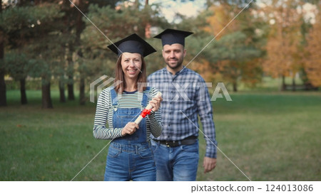 Joyful graduates enthusiastically celebrate their remarkable achievements together in a stunning autumn park setting 124013086