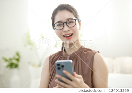 Young woman sitting in bed and looking at her smartphone Young woman sitting in bed and looking at her smartphone 124013269