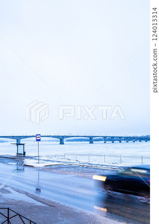 wet road along frozen river in blue twilight 124013314