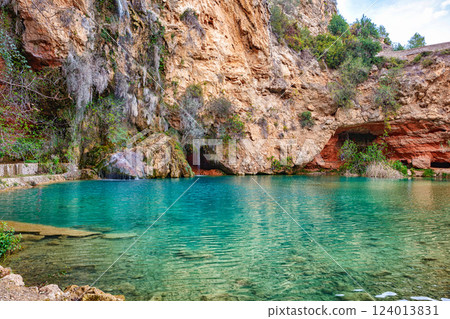 Tranquil Blue Lagoon Surrounded by Rocky Cliffs and Greenery in Spain During Daylight Tranquil Blue Lagoon Surrounded by Rocky Cliffs and Greenery in Spain During Daylight 124013831