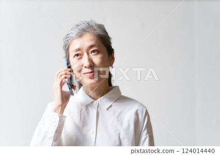 A middle-aged woman smiling while talking on her smartphone 124014440