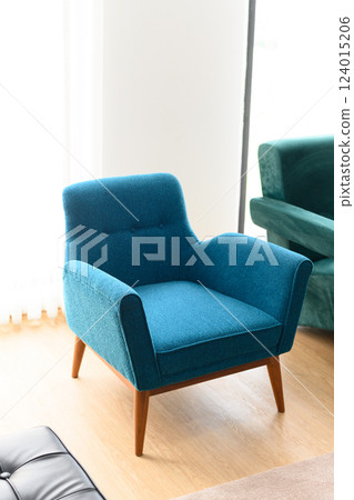 Blue armchair in bright room with wooden floor Blue armchair in bright room with wooden floor 124015206
