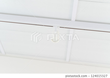 Minimalist white ceiling with single spotlight fixture 124015327