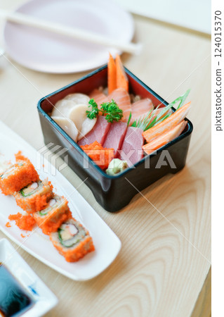 Fresh sashimi and sushi rolls served on wooden table 124015370