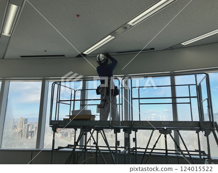 Workers installing air conditioners on the pedestal of an office building 124015522