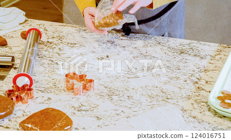 Using an adjustable rolling pin to roll out gingerbread cookie dough on the elegant marble counter in a modern kitchen, getting ready for festive holiday baking. Using an adjustable rolling pin to roll out gingerbread cookie dough on the elegant marble counter in a modern kitchen, getting ready for festive holiday baking. 124016751