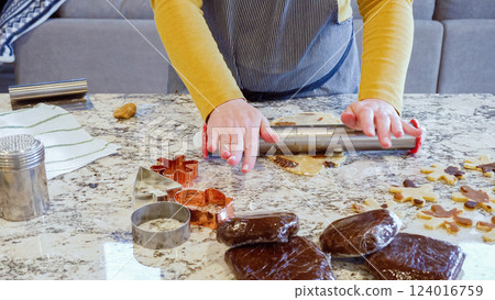 Using an adjustable rolling pin to roll out gingerbread cookie dough on the elegant marble counter in a modern kitchen, getting ready for festive holiday baking. 124016759