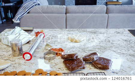 Using an adjustable rolling pin to roll out gingerbread cookie dough on the elegant marble counter in a modern kitchen, getting ready for festive holiday baking. 124016761