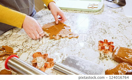 Using various festive cookie cutters, we're cutting out charming gingerbread cookies from the rolled dough on the sleek marble counter, bringing holiday cheer to the modern kitchen. Using various festive cookie cutters, we're cutting out charming gingerbread cookies from the rolled dough on the sleek marble counter, bringing holiday cheer to the modern kitchen. 124016764
